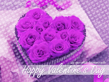 a heart shaped box filled with purple roses with the words happy valentine 's day below it