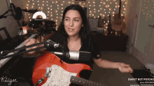 a woman playing a guitar in front of a microphone with the words sweet but psycho written on the bottom