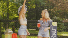 two women are standing in front of a lemonade stand with a sign that says ' ice ' on it