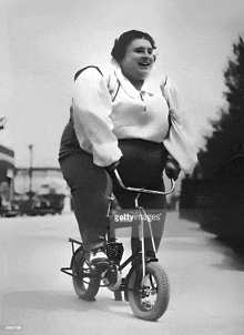 a black and white photo of a woman riding a small motorcycle with a license plate that says ' sss '