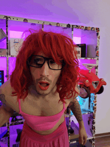 a man with red hair and glasses is wearing a pink bra and skirt