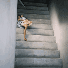 a woman is laying on a set of stairs with her head down