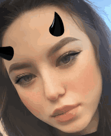 a close up of a girl 's face with a devil horn on her forehead