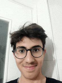 a young man wearing glasses and a black shirt is smiling