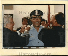 a man in a police uniform is being interviewed by another man