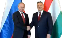 two men are shaking hands in front of a russian and hungarian flag