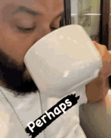 a man is drinking from a white cup with perhaps written on his shirt