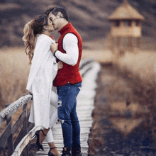 a man and a woman are kissing on a wooden bridge .