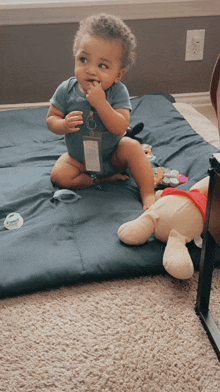 a baby with a lanyard around his neck is sitting on a blanket