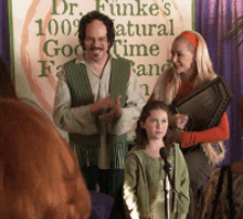 a group of people standing in front of a sign that says dr funke 's 100 % natural good time farm