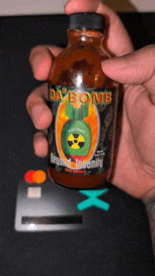 a person holding a bottle of day bomb hot sauce