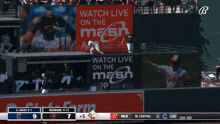 a baseball game is being played in front of a large screen that says on the nash app