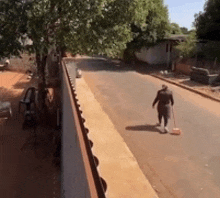 a man with a broom is walking down a street