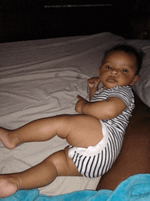 a baby is laying on a bed with a blue blanket