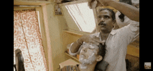 a man is shaving another man 's head in a room with a sign that says ' emergency exit '