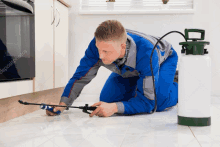 a man is kneeling on the floor with a spray bottle