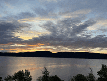 a large body of water with mountains in the background at sunset