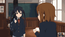 two anime girls are standing in a classroom with one holding a cake