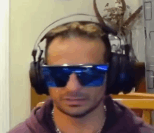 a man wearing headphones and blue sunglasses is making a funny face .