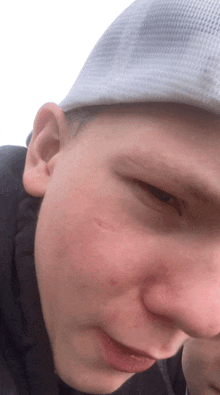 a close up of a young man 's face wearing a white hat