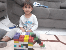 a young boy is playing with lego blocks in front of a guitar that says ' yamaha ' on it