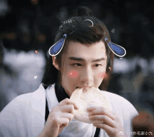 a man with a bun on his head is eating a bread