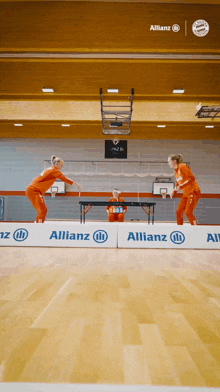 a group of people playing a game of ping pong on a court with a banner that says allianz on it