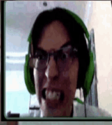 a man wearing glasses and green headphones is making a funny face