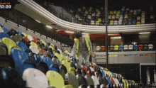 a man in a yellow vest stands in a stadium with a sign that says game in at the top