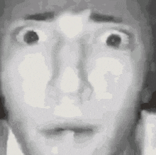 a black and white photo of a person 's face with a surprised look on their face .