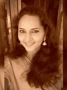 a woman with long hair and earrings smiles for a picture