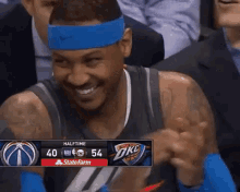 a basketball player wearing a blue headband is smiling in front of a scoreboard that says halftime at the top