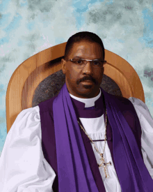 a priest wearing a white robe and a purple stole is sitting in a wooden chair