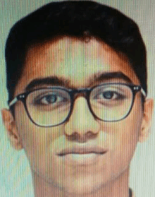 a young man wearing glasses is looking at the camera with a blurred background .