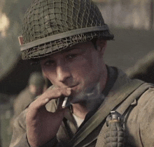 a soldier is smoking a cigarette while wearing a helmet .