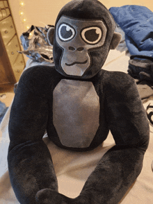 a stuffed gorilla is sitting on a bed with a dresser in the background