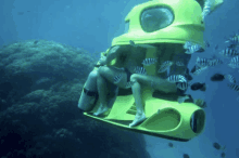 a person is sitting on a yellow submarine in the ocean