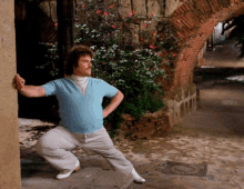 a man in a blue shirt and white pants is standing in front of a brick archway