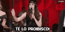 a woman is singing into a microphone and saying te lo proibico