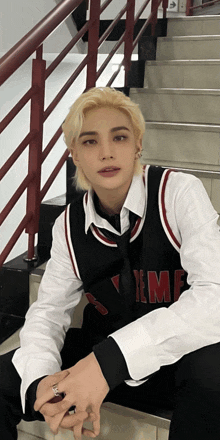 a young man is sitting on a set of stairs wearing a vest that says yme