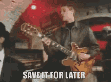 a man is playing a guitar with the words save it for later written on the bottom .