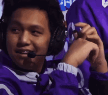 a man in a purple jacket is wearing a headset and smiling