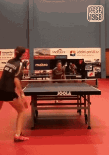 a woman playing ping pong on a table that says joola on it