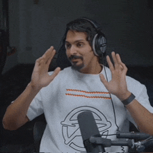 a man wearing headphones is sitting in front of a microphone making a gesture