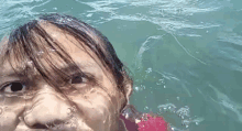 a little girl is swimming in the ocean and taking a selfie .