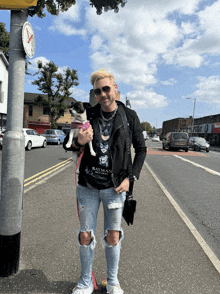 a man wearing a batman t-shirt is holding a small dog