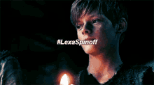 a close up of a person holding a lit candle with #lexaspinoff written on the bottom