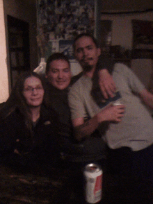 two men and a woman are posing for a picture with a can of soda in the middle