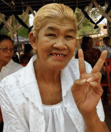 a woman with blonde hair and missing teeth is giving a peace sign