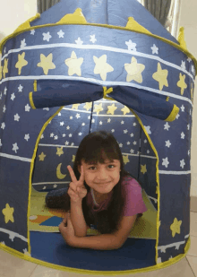 a little girl is laying in a tent with stars and the moon on it